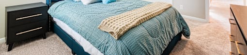 A bedroom with a blue headboard and a bed with a green comforter.