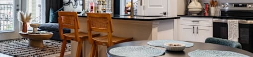 A kitchen with a table and chairs in front of it. at Evolve Waterford Apartments in Belville, NC