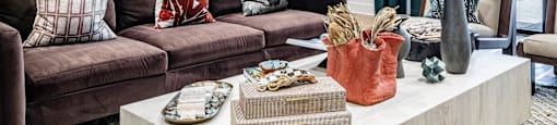A clubhouse with a brown couch and a coffee table with various objects on it at Evolve Waterford Apartments in Belville, NC