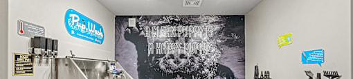 A room with a large poster of a bear on the wall and a stainless steel tank on the left side.