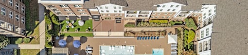 An aerial view of a pool surrounded by buildings and trees.