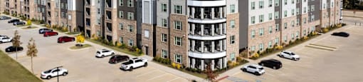 A large apartment complex with a parking lot in front at Liam at Hays Farm in Huntsville, Alabama