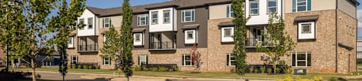 A row of modern apartment buildings with trees in front at Liam at Hays Farm in Huntsville, Alabama