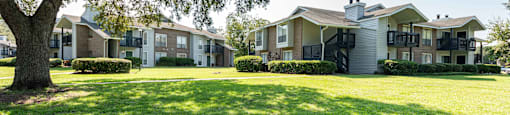 A row of houses with green lawns and trees in front.