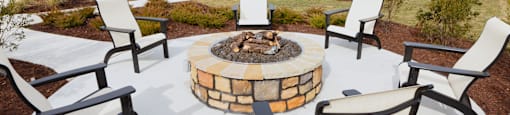 A fire pit surrounded by chairs in a backyard.
