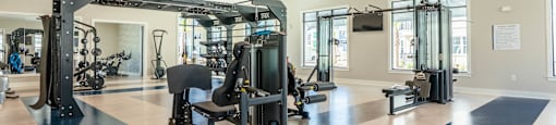 A gym with a variety of equipment including a weight bench, a squat rack, and a treadmill.