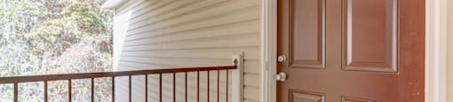 A brown door is on the right side of a white wall.