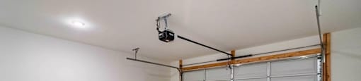 A large empty room with a white wall and a closed white garage door.