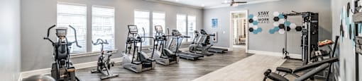 A spacious gym with a variety of equipment and a sign that says "STAY WARM".
