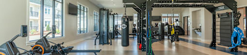 A gym with a row of exercise bikes and a TRX suspension trainer at Arbors at Morehead City apartments in Morehead City, NC.