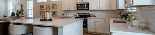 A kitchen with a white island and bar stools.