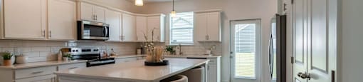 A kitchen with white cabinets and a large island.