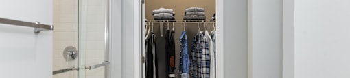 a walk in closet in a 555 waverly unit with a glass shower