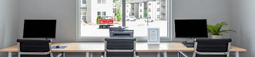 an empty office with three desks and chairs and a window