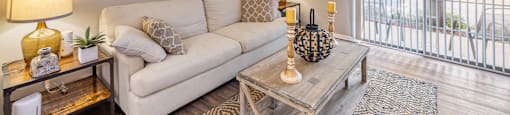 A well-lit living room with a white couch, a glass coffee table, and a yellow lamp.