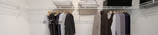 a walk in closet with a rack of clothes and shoes