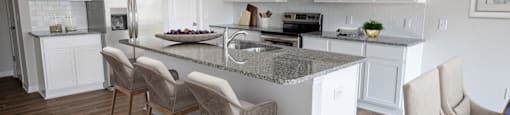 a kitchen with white cabinets and a marble counter top