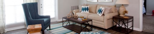 A living room with a blue chair, a white couch, and a ceiling fan at 1287 Shoals apartments in Athens, GA.