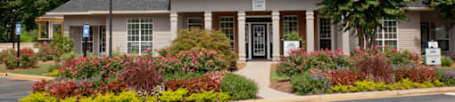 A clubhouse for 1287 Shoals apartments in Athens, GA with a grey roof and a sign on it.
