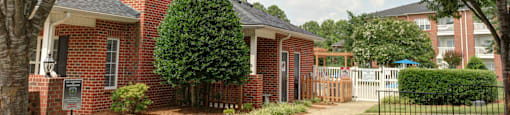 A red brick house with a black fence in front.