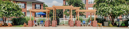 A pool surrounded by a wooden pergola and a brick wall.