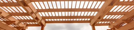 A wooden pergola overlooks a swimming pool.