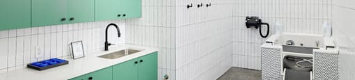 A modern kitchen with green cabinets and white tiled walls.