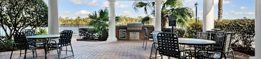 a patio with tables and chairs and a view of the water