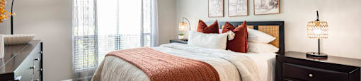 A bedroom with a large bed and a window with curtains.