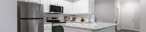 A kitchen with a stainless steel refrigerator, microwave, and oven.