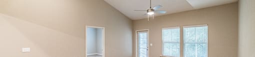A room with a ceiling fan and a door leading to another room.