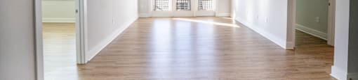 A spacious room with wooden floors and white walls.