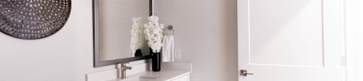 A bathroom with a white cabinet and a mirror above it.