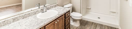 A bathroom with a toilet, sink, and shower.