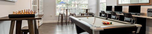 a game room with a pool table and a bar with chairs