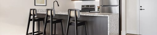 A modern kitchen with a bar stool and a fridge at Boardwalk at Research Park apartments in Huntsville, AL.