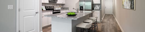 an open kitchen with a large island with a granite counter top