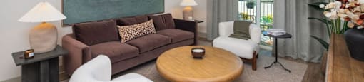 A living room with a brown couch, a white chair, and a wooden coffee table at Liam at Hays Farm in Huntsville, Alabama