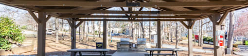 A covered picnic area with tables and benches at Madison Woods apartments in Greensboro, NC.