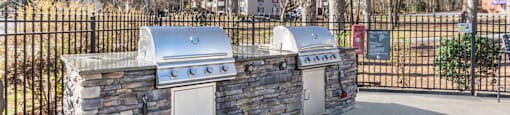 A stone wall with two built-in grills on top. at Madison Woods apartments in Greensboro, NC