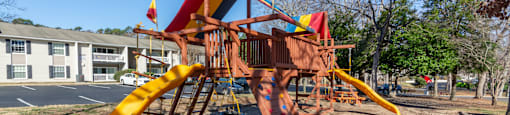 A playground with a yellow slide and a red and yellow structure at Madison Woods apartments in Greensboro, NC.