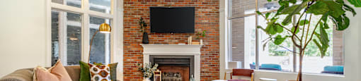a living room with furniture and a brick fireplace