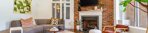 a living room with a brick fireplace and a rug
