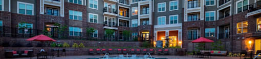 A swimming pool in front of a multi-story apartment building.