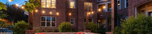 A patio with a brick wall and a large sectional for seating.