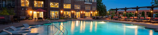 Swimming pool in front of a multi-story apartment building at dusk.
