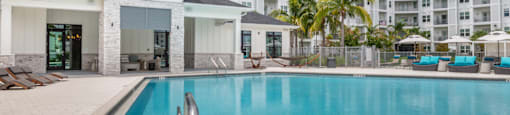 A swimming pool in front of a building with a white and beige exterior.