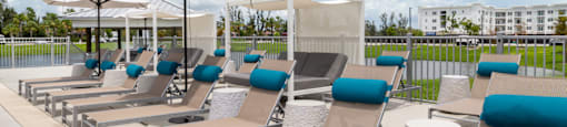 A row of sun loungers are arranged on a patio.
