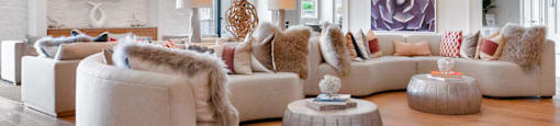 A modern living room with a white couch and a large painting on the wall.