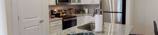 a kitchen with a granite counter top and a stainless steel refrigerator